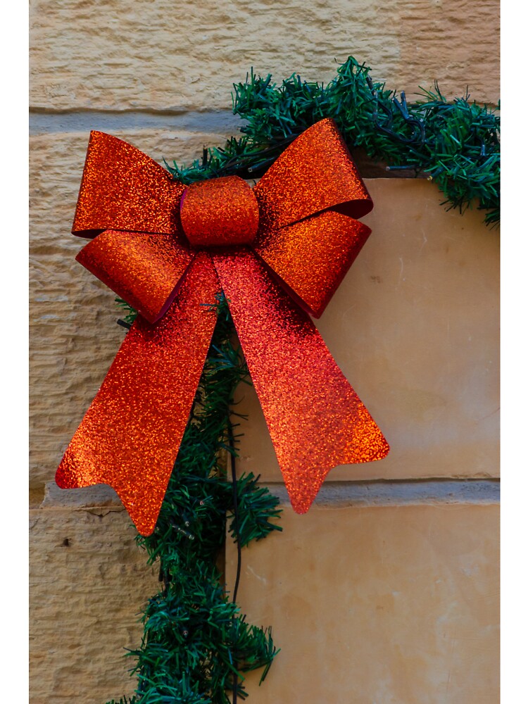 Sparkling Red Bow Christmas Decoration On Green Garland Against Stone Wall For Holiday Display by Nmallia